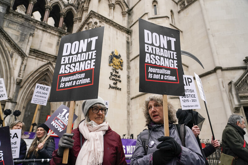 Protesters hold up signs with messages opposing the extradition of Julian Assange outside of a London courthouse on Jan. 24. (AP/Yonhap News)