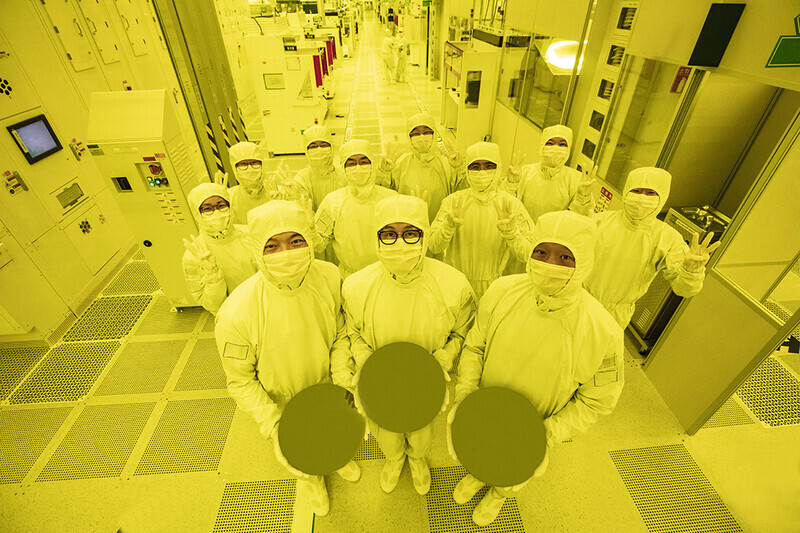 Samsung employees hold up three 3nm wafers at the company’s production line. (provided by Samsung Electronics)