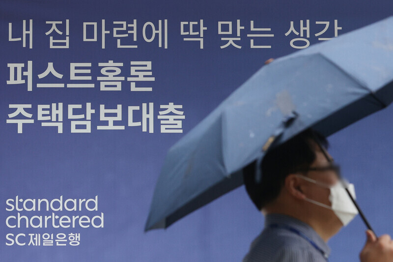 A person walks by a sign advertising home loans outside a bank in Seoul on Aug. 25. (Yonhap News)