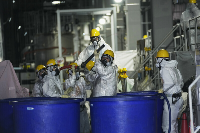 Workers at the Fukushima Daiichi nuclear power plant can be seen wearing protective suits while removing radioactive material from the contaminated water in March 2022. (AP/Yonhap)