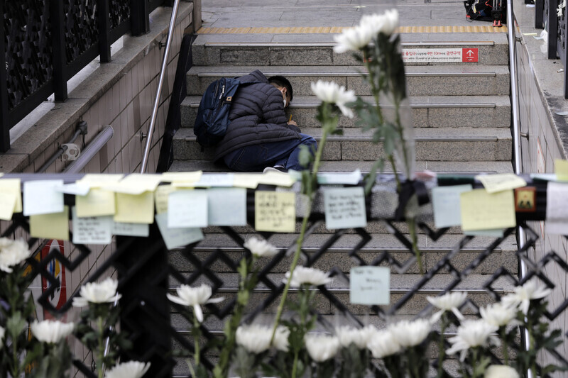 A person sits on the steps leading out of Itaewon Station’s Exit 1, near the site of the deadly crowd crush on Halloween weekend, to write a message to victims on Nov. 1 (Kim Myoung-jin/The Hankyoreh)