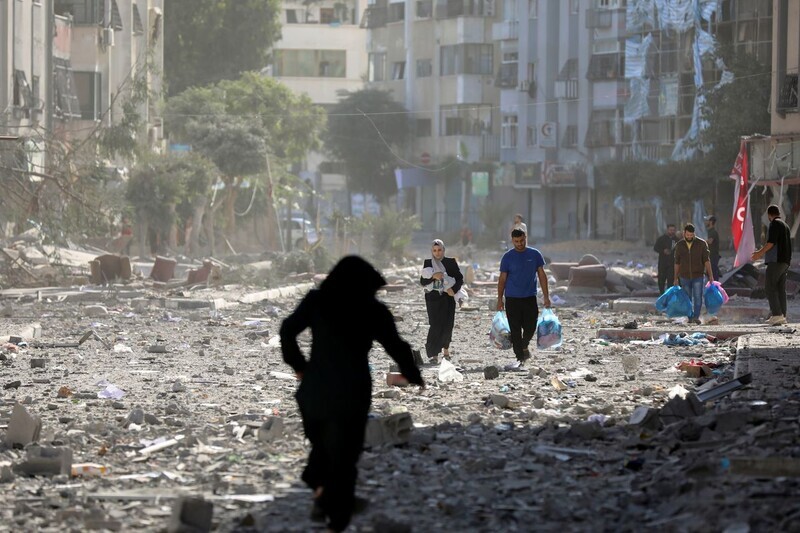 Residents of Gaza walk through rubble from Israel’s air strikes as they leave their homes on Oct. 30 amid the ongoing conflict between Israel and Hamas. (AP/Yonhap)