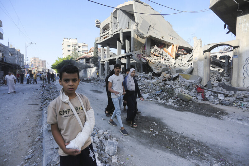 A young boy with his arm in a sling looks at the camera as he stands amid the rubble of buildings destroyed by Israel’s bombing of Rafah, southern Gaza, on Nov. 7. (AP/Yonhap)