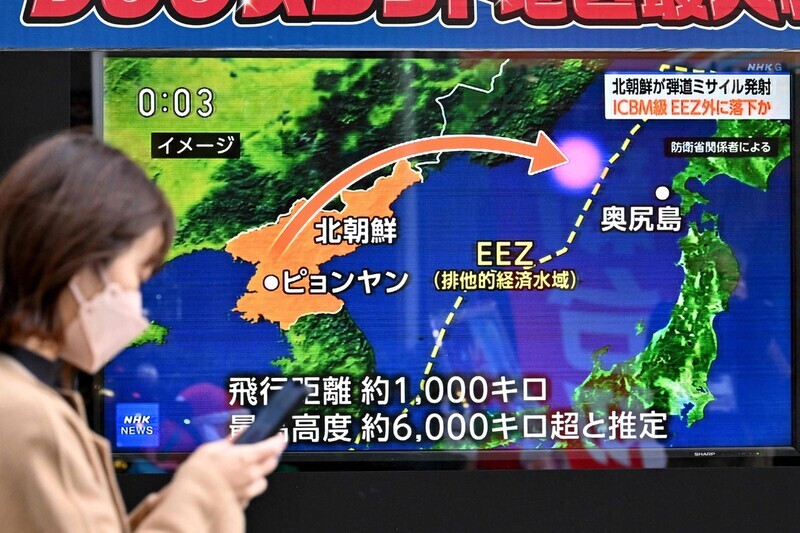 A person walks by a television screen in Tokyo, Japan, broadcasting news about the latest missile launches by North Korea on Dec. 17-18. (AFP/Yonhap)