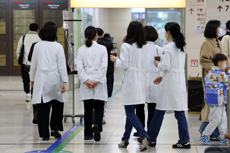 Hospital staff in lab coats walk through the lobby of Chonnam National University Hospital in Gwangju on Feb. 19, 2024. (Yonhap)