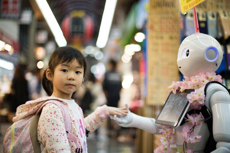 A child interacts with a service robot. (Andy Kelly/Unsplash)