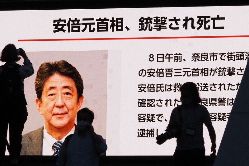 The silhouettes of people can be seen in front of a monitor showing news of the death of former Japanese Prime Minister Shinzo Abe on July 8. (AFP/Yonhap News)