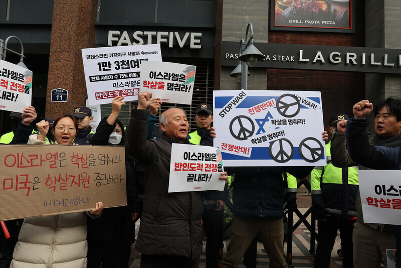 Participants in a rally outside the Israeli Embassy in Seoul on Nov. 23 hold up signs calling for an end to Israel’s massacre in Gaza and US support for Israel’s massacre of Palestinians. (Baek So-ah/The Hankyoreh)