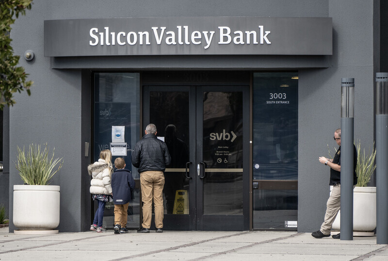 People stand outside of Silicon Valley Bank in Santa Clara, California, on March 11 reading a notice posted on the door. (UPI/Yonhap)