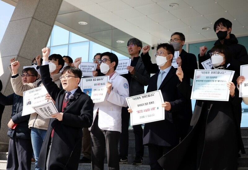 Faculty at Jeonbuk National University Medical School and its attached hospital protest the increase in the medical school enrollment cap from 142 to 200 outside the school’s administration building on March 20, 2024. (Yonhap)