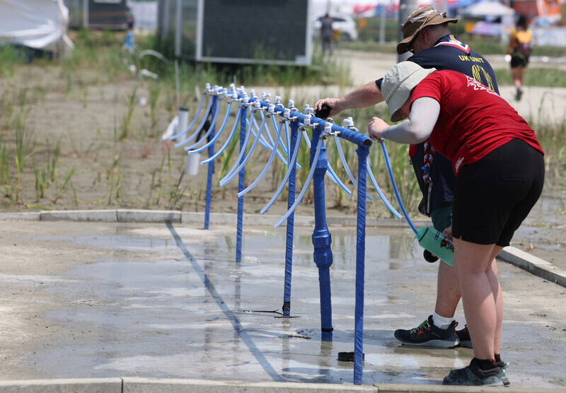 Participants in the Saemangeum World Scout Jamboree held in North Jeolla Province fill water bottles in the scorching heat on Aug. 2. (Yonhap)