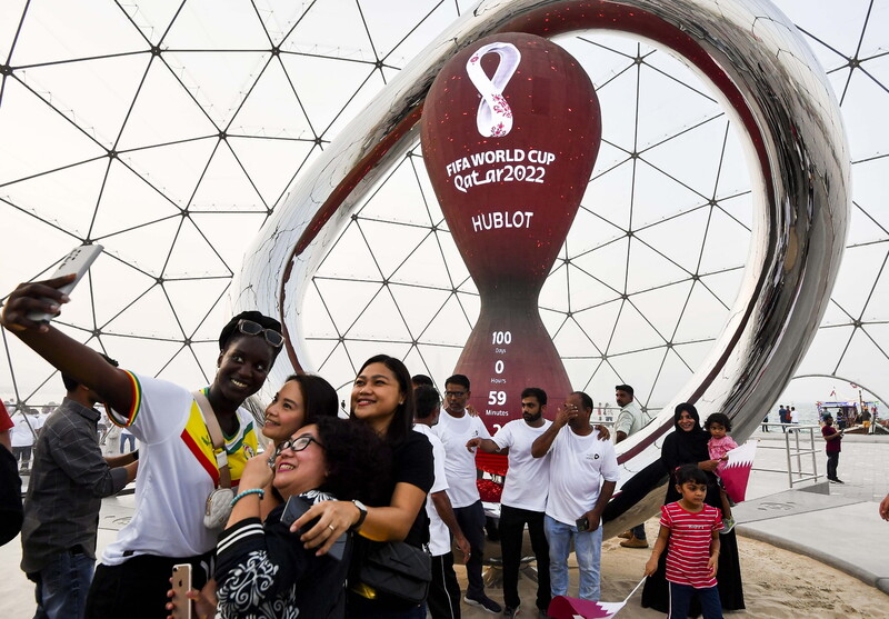 12日（現地時間）、カタールのドーハで2022年ワールドカップのカウントダウンを前に、サッカーファンが記念撮影をしている. ドーハ/EPA 聯合ニュース