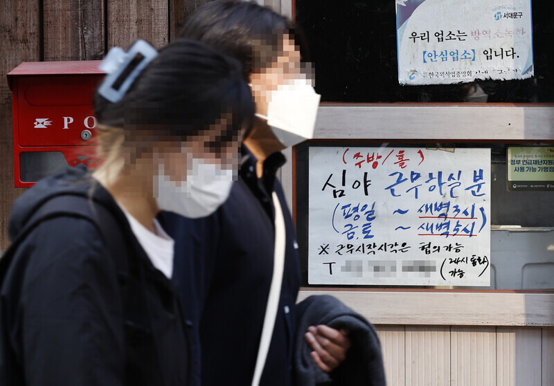 People pass by an advertisement for the night shift in a restaurant in this undated photo. (Yonhap News)