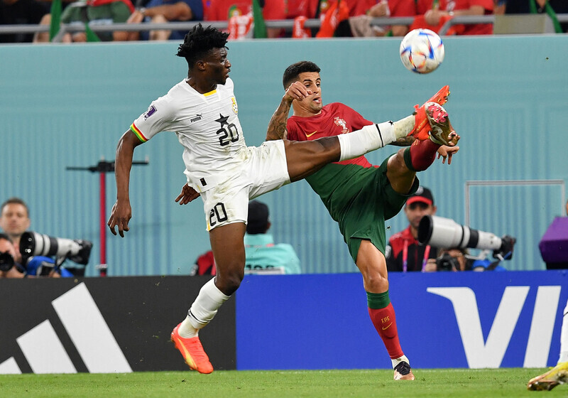 Mohammed Kudus of Ghana (left) spars Joao Cancel of Portugal for the ball during the two teams’ matchup on Nov. 25 (Korea time) in Doha, Qatar. (Reuters/Yonhap)
