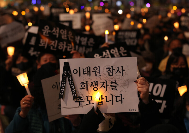 People at a memorial rally for victims of the Itaewon crowd crush hold up candles and signs on Nov. 5. (Shin So-young/The Hankyoreh)