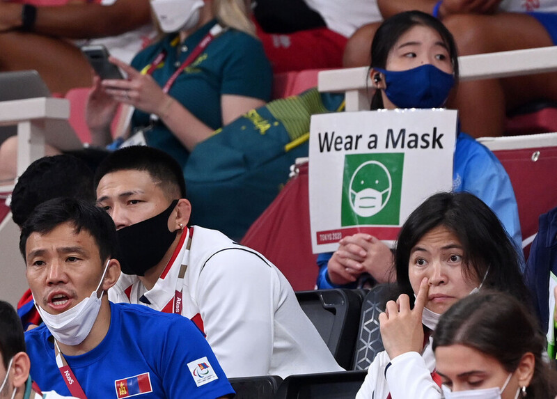 28일 일본 도쿄 일본 무도관에서 열린 유도 경기에서 관계자들이 마스크를 벗은 채 응원을 하고 있다. 바로 뒤에는 자원봉사자가 마스크 착용을 알리는 손팻말을 들고 있다. 도쿄/올림픽사진공동취재단