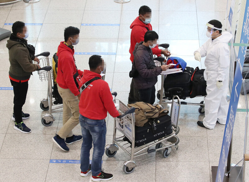 A disease control staffer directs arriving international travelers at Incheon International Airport’s Terminal 1 on the morning of Feb. 4, amid reports of South Korea’s first domestic cluster infection involving a virus variant originating in the UK. (Yonhap News)