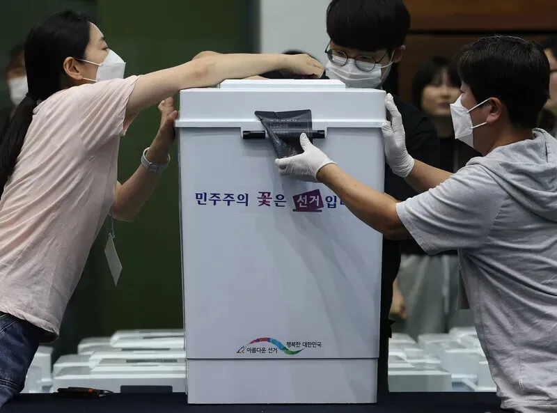 Ballot counters unseal a ballot box for early votes at a gymnasium at Seoul National University on June 3, 2026. (Yonhap)