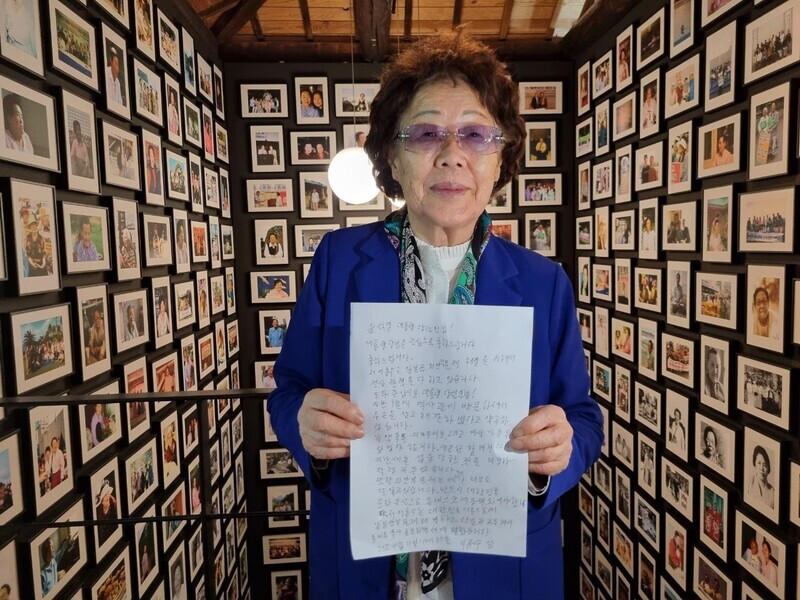 Lee Yong-soo holds up a letter to President-elect Yoon Suk-yeol while standing in front of an exhibit of photos of Korean survivors of the “comfort women” system at the Museum of Military Sexual Slavery by Japan in Deagu’s Jung District on April 13. (Park Go-eun/The Hankyoreh)