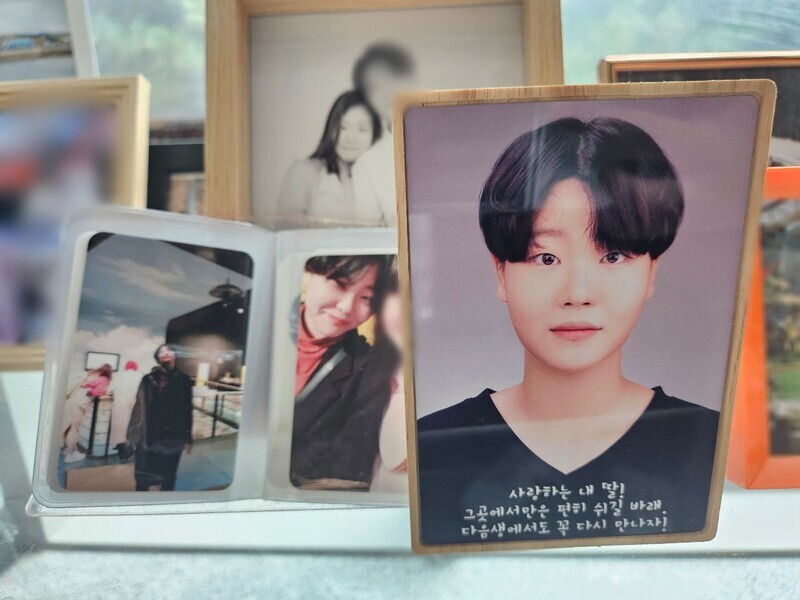Photos of Park Seon-bin, who lost her life in an industrial accident at SPL’s factory in Pyeongtaek on Oct. 15, 2022, fill a corner of the shelf where Park’s urn is kept. (Jang Hyeon-eun/The Hankyoreh)