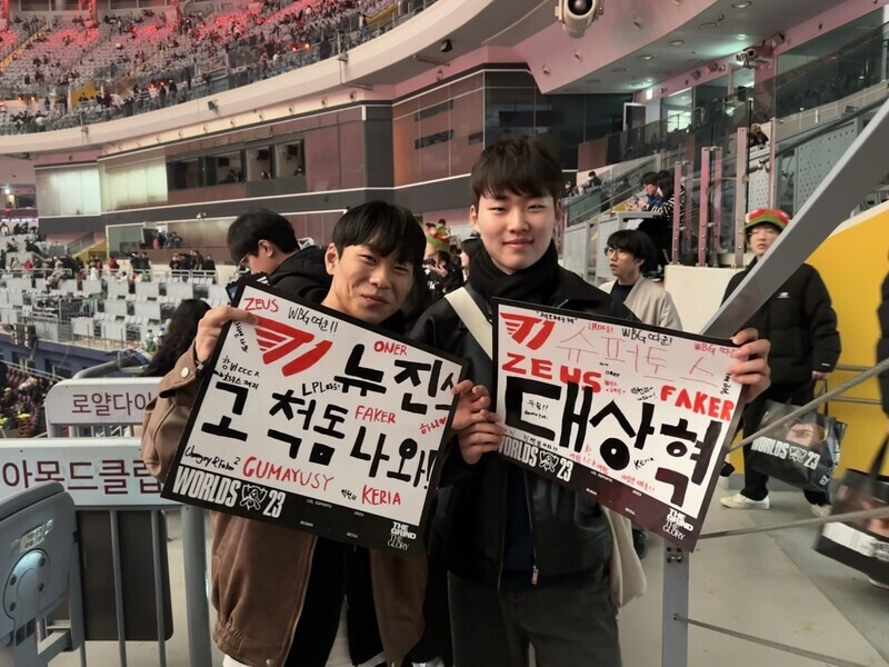Lee Chang-geon (left) and Jeong Hwa-yun, two college students, hold up handwritten signs cheering on T1 in the LoL World Championship finals held at Gocheok Sky Dome on Nov. 19. (Chung In-seon/The Hankyoreh)