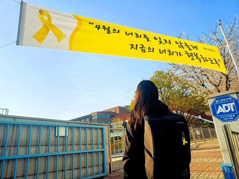 Yu Su-hyeon, a second-year student at Kyung-an High School in Ansan walks under a banner at the gate of her school commemorating the victims of the Sewol ferry tragedy of 2014. (Lee Jun-hee/The Hankyoreh)
