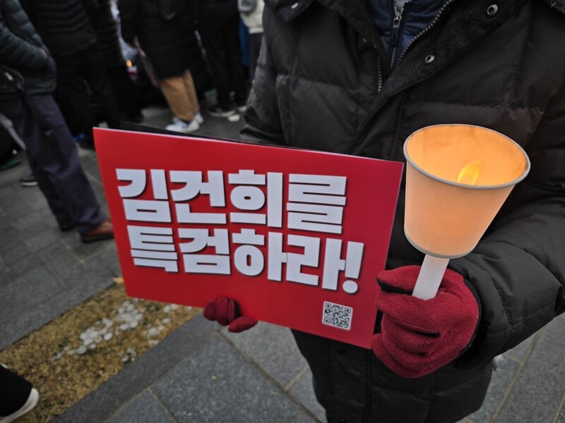 30일 저녁 서울 광화문에서 열린 ‘윤석열을 거부한다 3차 시민행진’에 참여한 시민이 두터운 옷을 입고 촛불과 손팻말을 들고 있다. 김가윤 기자