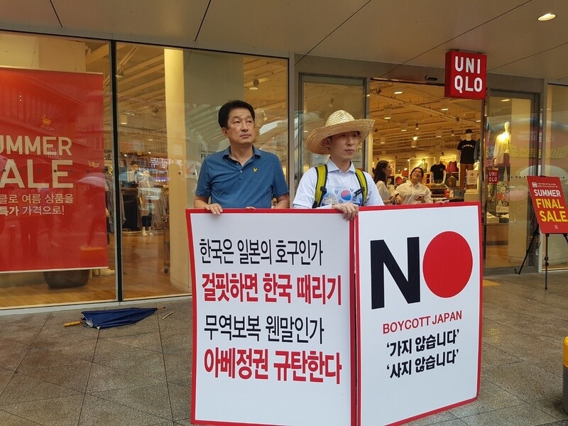 Two South Koreans behind a sign advocating a boycott on travel to Japan next to a memorial plaque for the June Democracy Movement of 1987 in Daegu on July 20. (Kim Il-woo