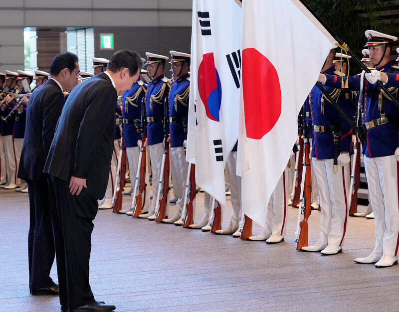 President Yoon Suk-yeol of South Korea and Prime Minister Fumio Kishida of Japan bow before their national flags ahead of their summit in Tokyo on March 16, 2023. (Reuters)