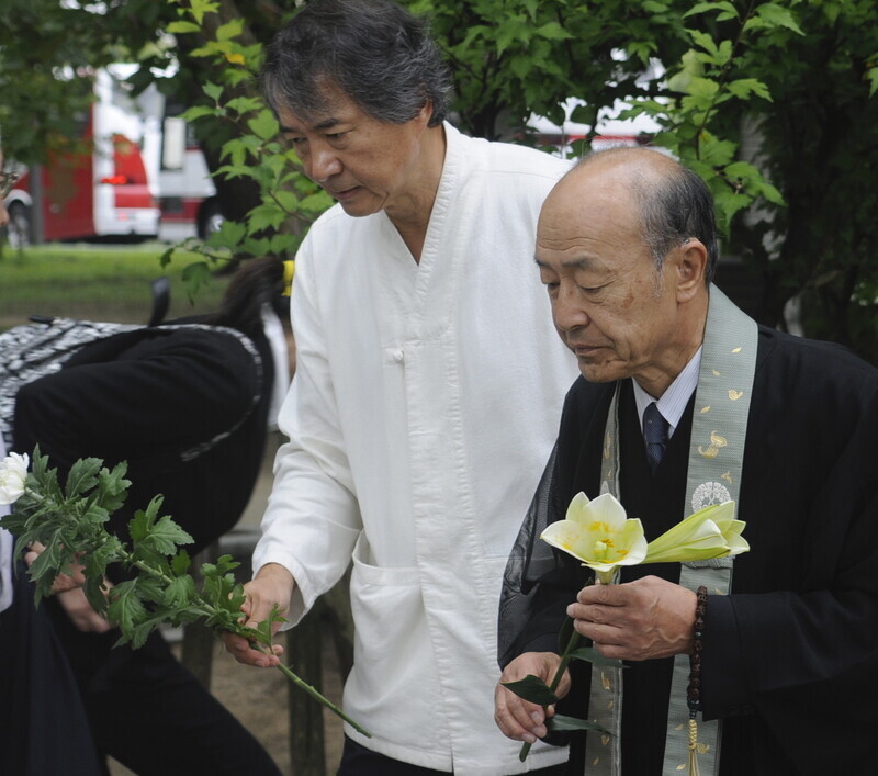 Yoshihiko Tonohira and Chung Byung-ho lay down flowers at a memorial service on Sept. 17, 2015, for forced Korean laborers whose remains were dug up in Japan. (Chung Byung-ho)