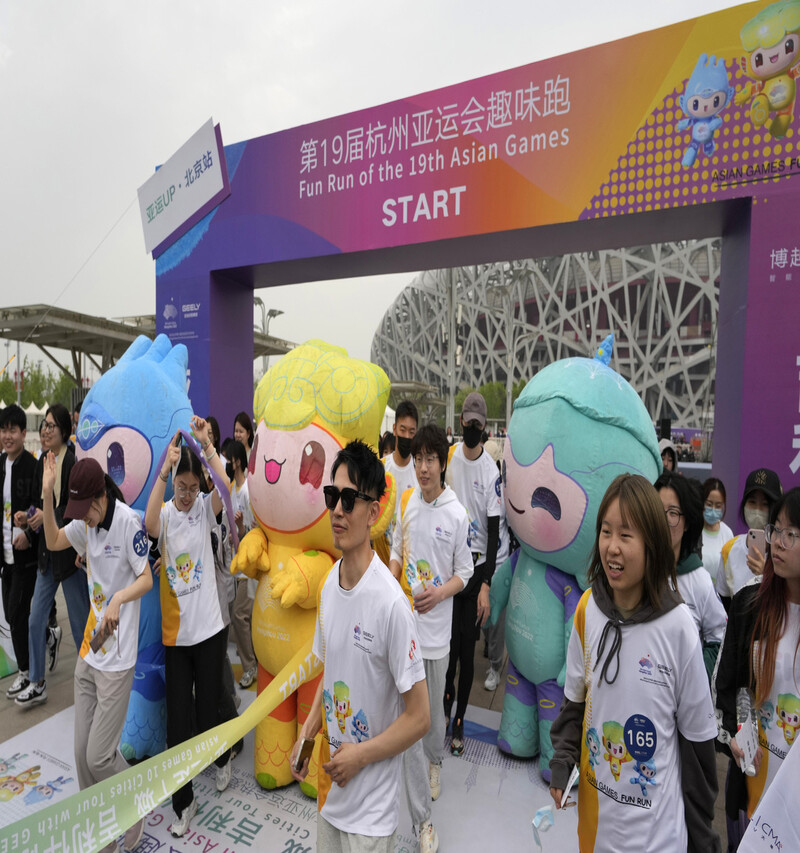 4月27日に中国・北京で行われたアジア大会の広報イベントで市民に挨拶する杭州アジア大会のマスコット、チェン・チェンさん（左から）、チュンチョンさん、リアン・リアンさん。  AP通信