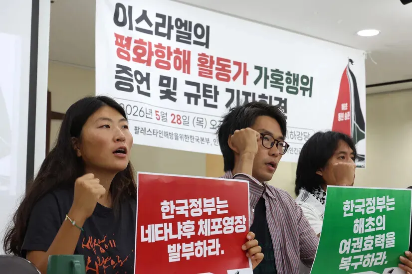 Kim A-hyun, Kim Dong-hyeok, and Jonathan Victor &ldquo;Seungjoon&rdquo; Lee &mdash; all activists released by Israel after being captured as they attempted to break the siege on Gaza and deliver aid &mdash; hold their fists up and chant during a press conference held at the Green Hospital in Seoul on May 28, 2026, where they testified about the abuse they faced at the hands of Israeli forces. (Choi Hyeon-su/Hankyoreh)