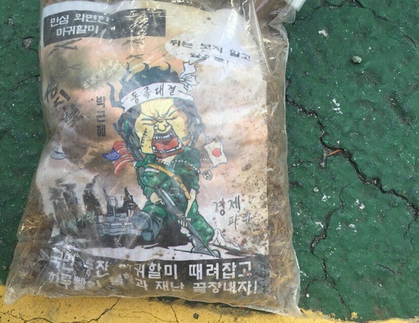 A bag of waste and fliers sent by North Korea across the border via balloon in 2016. The person depicted is labeled Park Geun-hye, the president of South Korea at the time. (courtesy of the Joint Chiefs of Staff)