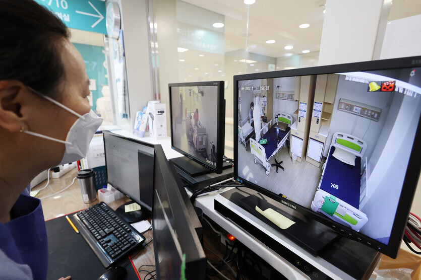 A medical worker at a dedicated COVID-19 hospital in Seoul’s Gwangjin District monitors beds with screens on Tuesday. (Yonhap News)