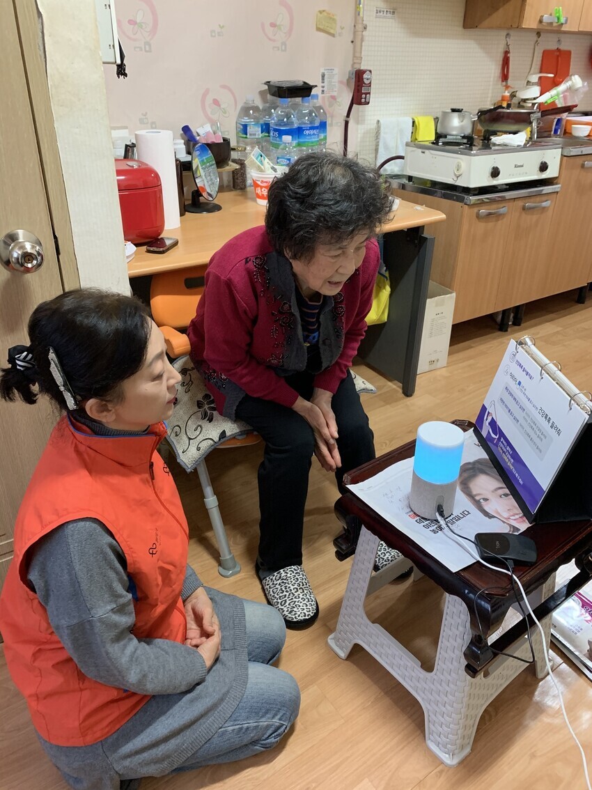 <b>A senior resident of Seoul’s Yeongdeungpo District learns how to use an AI care service in her home. (provided by SK Telecom)<br><br></b>