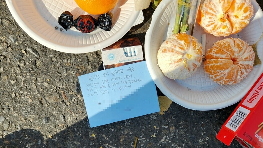 Memorial messages and offerings of snacks and cigarettes left by people fill the space outside Exit 1 of Itaewon Station on Nov. 7. (Park Ji-young/The Hankyoreh)