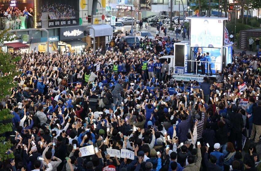 A crowd of people raise their phones at a campaign event for Jin Gyo-hoon, the Democrats’ nominee for Gangseo District mayor, on Oct. 9. (Yonhap)