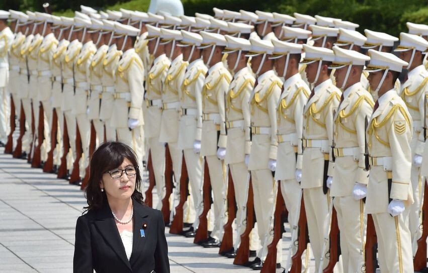 New Japanese Defense Minister Tomomi Inada walks past Self-Defense Forces guards during a welcome ceremony at the Ministry of Defense in Tokyo