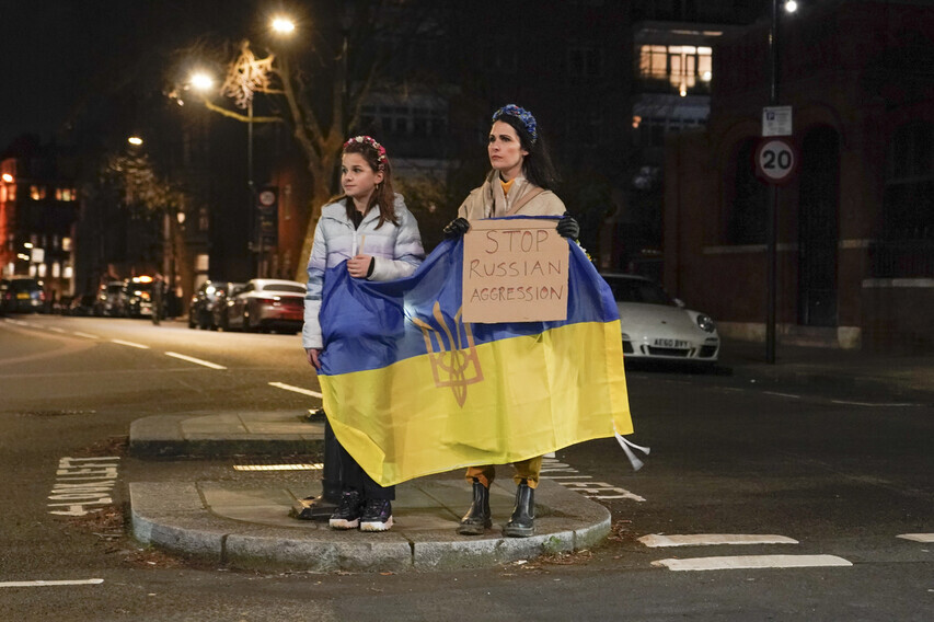 Two people holding a Ukrainian flag protest the Russian attack on Ukraine outside of the Russian Embassy in London, the UK, on Feb. 23. (AP/Yonhap News)