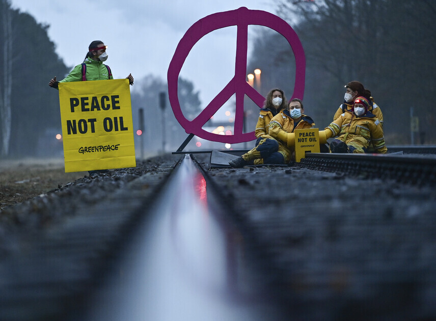 Activists with Greenpeace in Germany hold a sign reading “peace not oil” during a protest in March. (AP/Yonhap News)