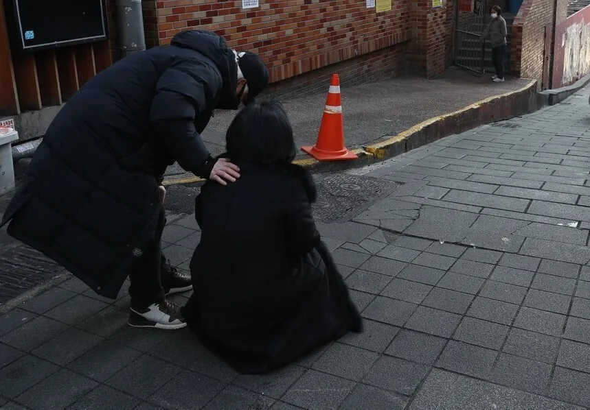 Jo Mi-eun, the mother of Itaewon crowd crush victim Lee Ji-han, weeps on the ground of the alleyway in Itaewon where the disaster occurred as she visits it for the first time since the tragedy with her husband, Lee Jong-cheol. (Kim Bong-gyu/The Hankyoreh)