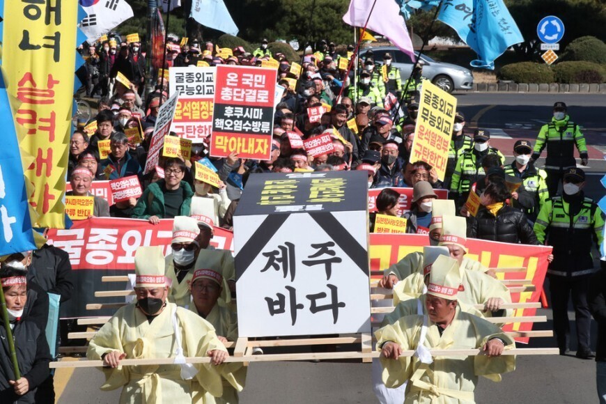 Members of farming and fishing organizations opposing Japan’s plan to release contaminated water from Fukushima hold a rally outside the Jeju Provincial Office in February, with some participants, pictured here, carrying a casket reading “Jeju’s oceans.” (Lee Jeong-yong/The Hankyoreh)