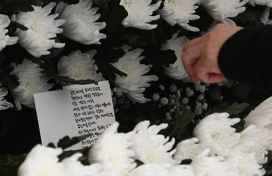 A handwritten note sits among white chrysanthemums on Nov. 1 at a joint memorial altar for those killed in the Itaewon crowd surge. (Yoon Woon-sik/The Hankyoreh)