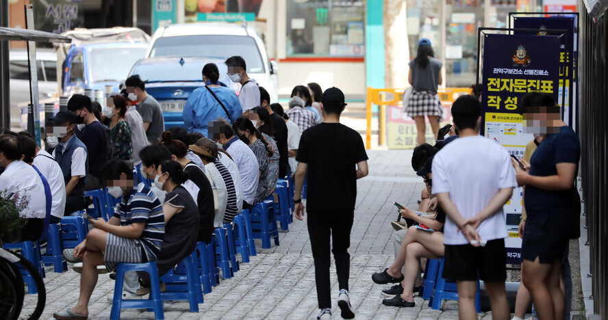 People wait in line to get tested for COVID-19 at a temporary screening center in Seoul on Tuesday. (Yonhap News)
