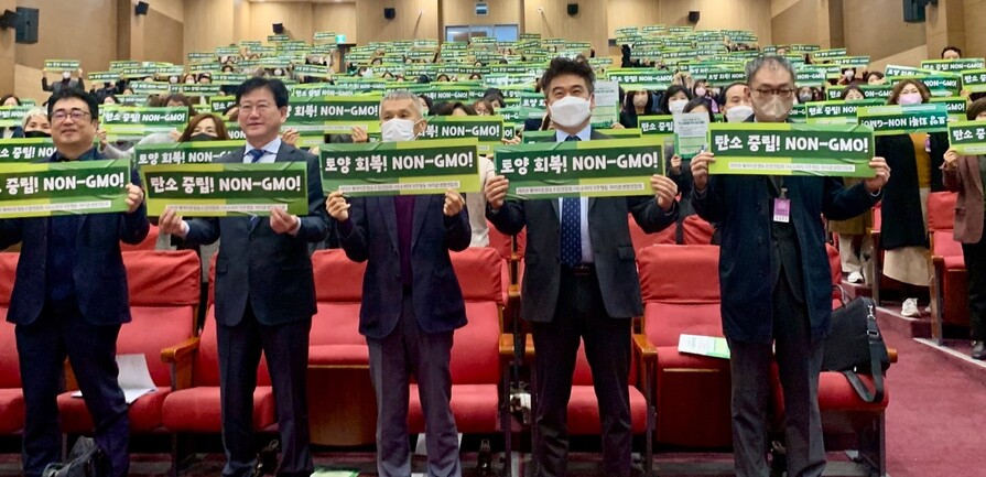 28일 서울 국회의원회관 대회의실에서 열린 ‘기후위기 해결을 위한 모색-탄소중립을 위한 농업 방향 토론회’ 참석자들이 ‘탄소 중립! 논지엠오(Non-GMO)!’ 등이 적힌 손팻말을 들고 있다.