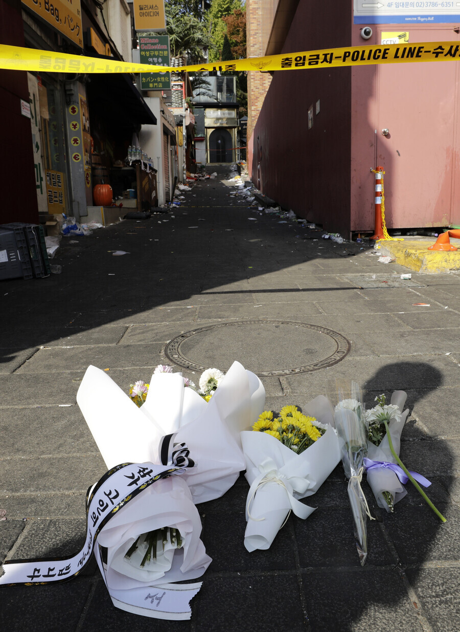 Bouquets of flowers sit on the ground at the entrance to the alleyway where a crowd crush took place in Itaewon, killing 156. (Kim Myoung-jin/The Hankyoreh)