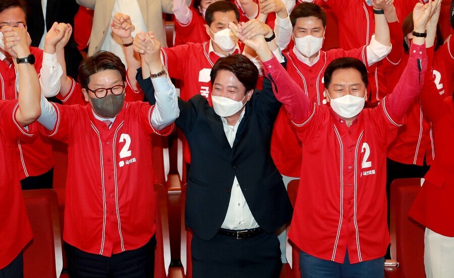 People Power Party leader Lee Jun-seok (center) cheers with party members including Kweon Seong-dong (left) and Kim Gi-hyeon (right) while watching exit polls come in on June 1. (National Assembly pool photo)