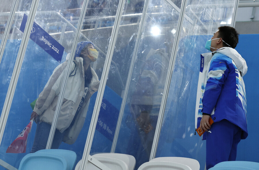 A member of the staff at the Beijing Winter Olympics speaks to his girlfriend through the glass dividers that make up the closed loop system on Feb. 6. (Reuters/Yonhap News)