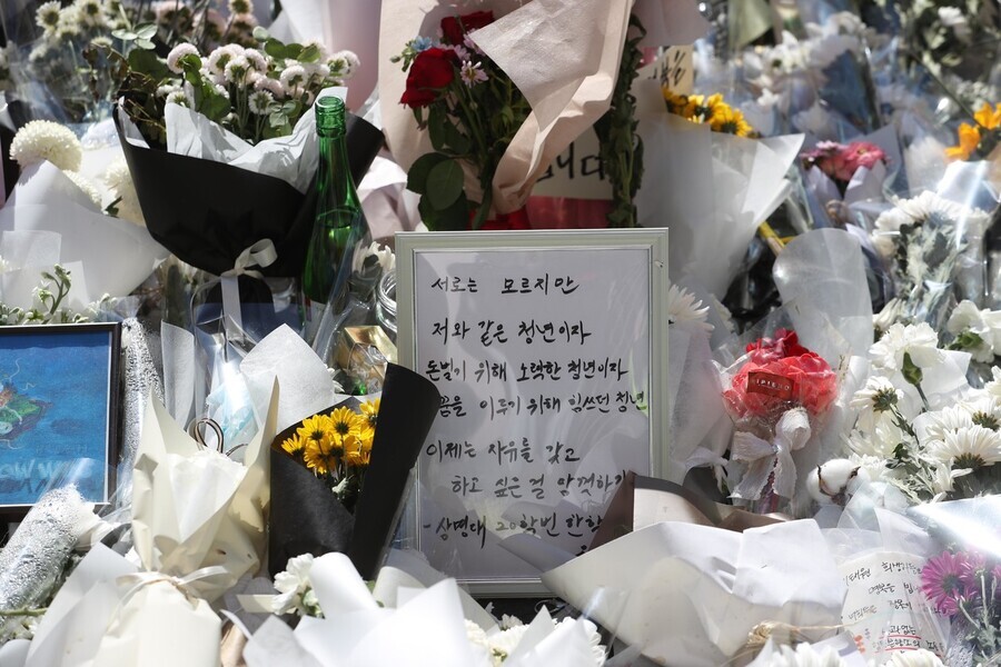 A framed letter to victims of the Itaewon crowd crush sits among flowers in a memorial space outside Exit 1 of Itaewon Station on Nov. 2. (Kang Chang-kwang/The Hankyoreh)