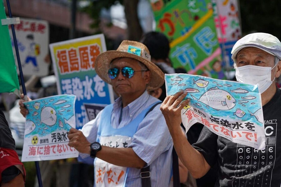 Protesters hold signs with messages opposing the release of contaminated water from the Fukushima Daiichi nuclear power plant at a rally outside the headquarters of TEPCO in Tokyo on Aug. 24. (AFP/Yonhap)